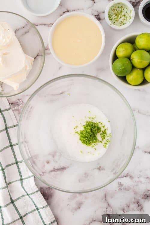 Close-up photo showing hands rubbing key lime zest into granulated sugar, a key step for infusing flavor into the No Bake Key Lime Pie.