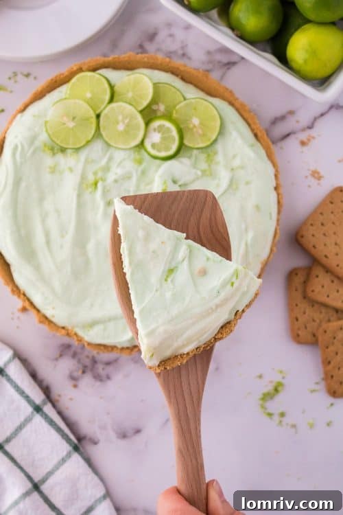 A perfectly sliced piece of No Bake Key Lime Pie on a white plate, showcasing its texture and ready to be eaten.