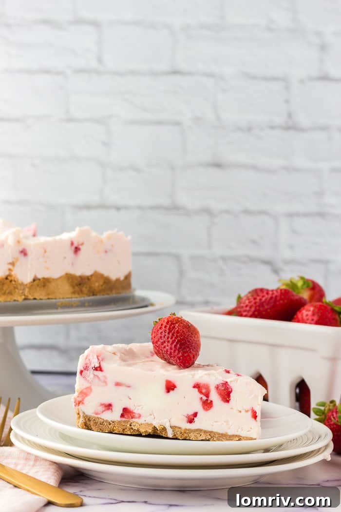 A vibrant slice of no-bake strawberry cheesecake on a white plate, showcasing its creamy texture and fresh strawberry pieces.