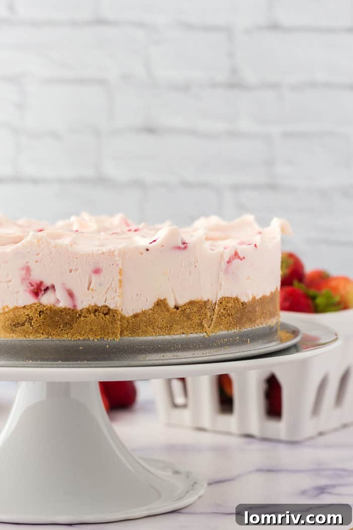 A fully assembled no-bake strawberry cheesecake presented on an elegant cake plate, ready for serving.