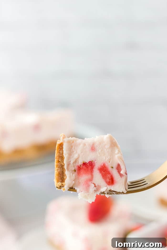A tantalizing bite taken from a slice of no-bake strawberry cheesecake, highlighting its texture and fresh fruit.