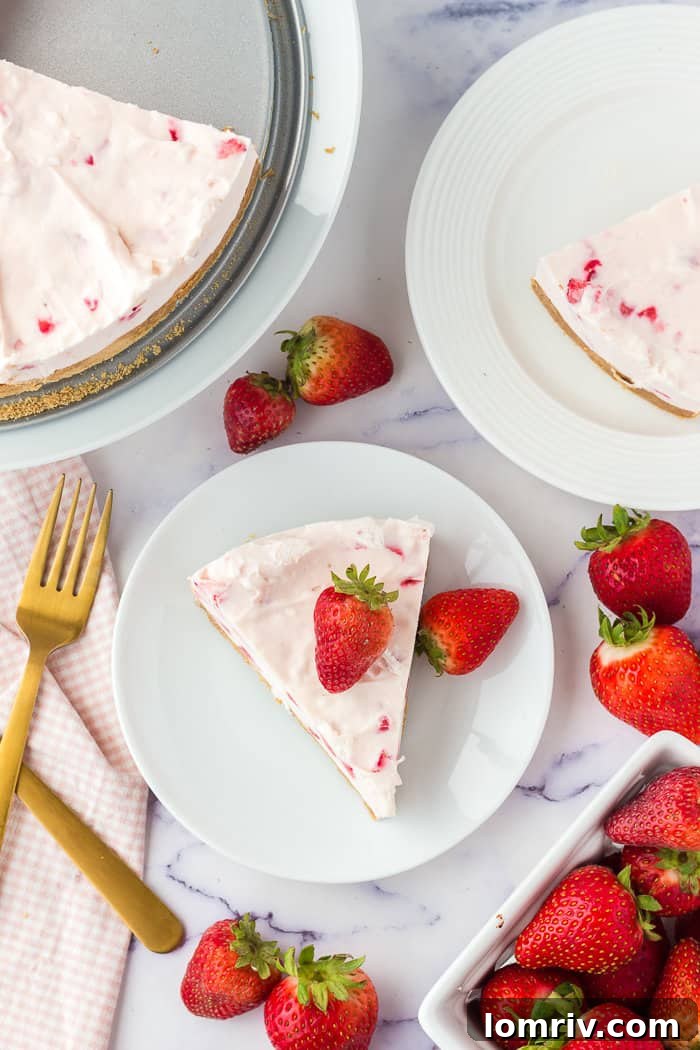 A close-up shot of a single slice of no-bake strawberry cheesecake on a plate, highlighting its smooth filling and berry pieces.