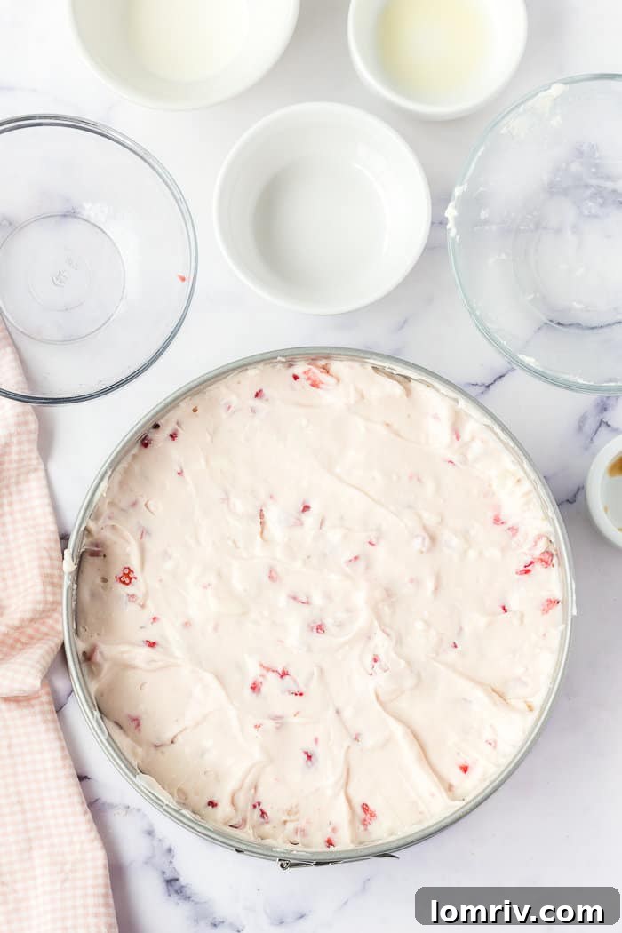 The no-bake strawberry cheesecake mixture poured into the springform pan, ready to be chilled.