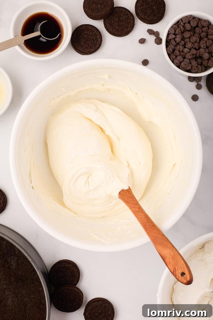 The second half of whipped cream being folded into the cheesecake mixture, completing the smooth and airy filling.