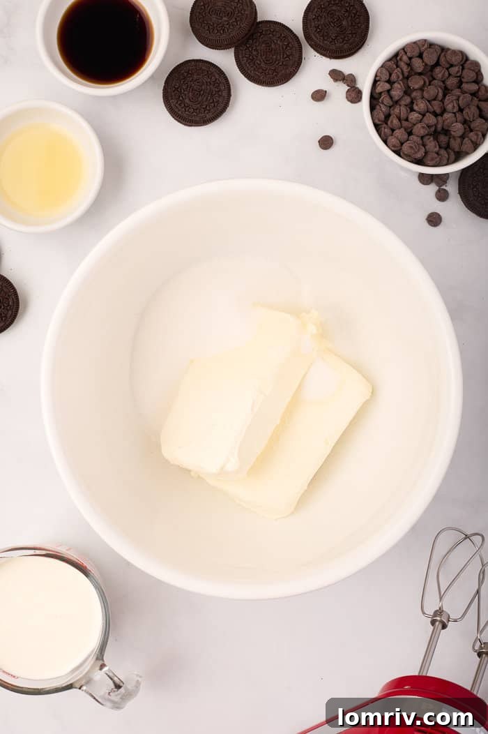 Cream cheese and granulated sugar being beaten together until smooth and creamy for the cheesecake filling.