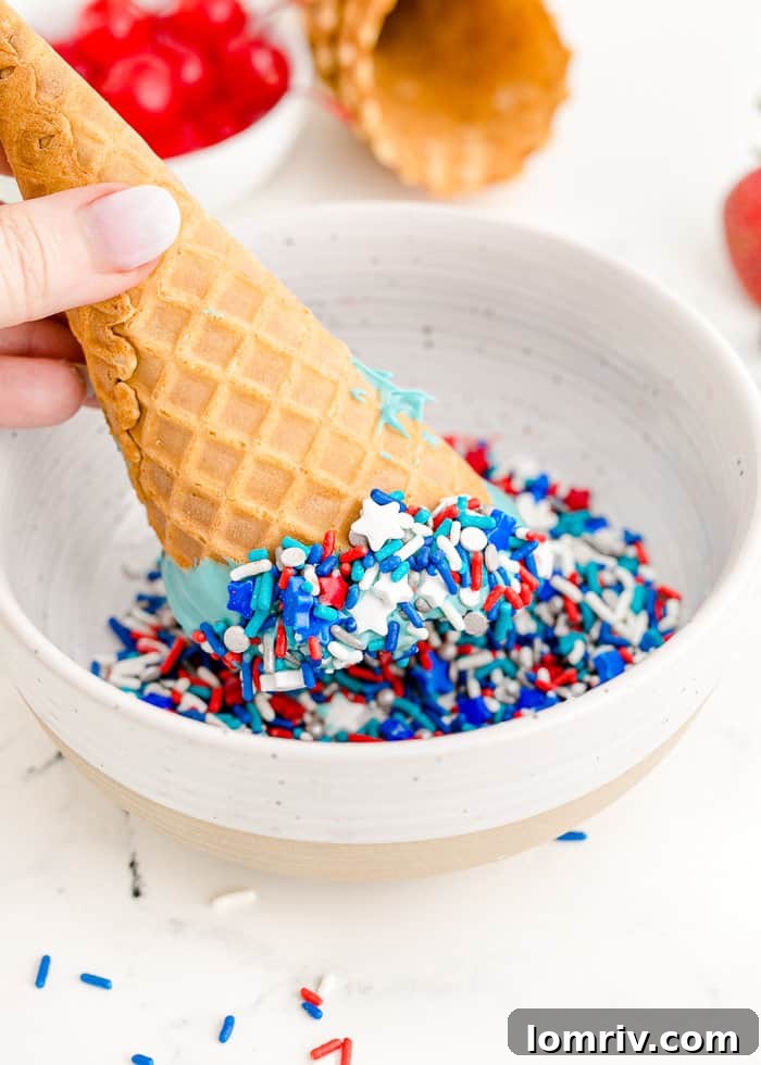 Red, white, and blue sprinkles being added to a freshly dipped waffle cone.
