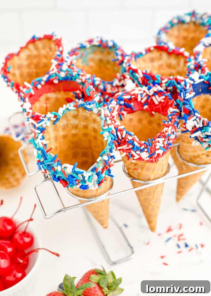 Decorated waffle cones with sprinkles, standing upright in a cone holder to chill.