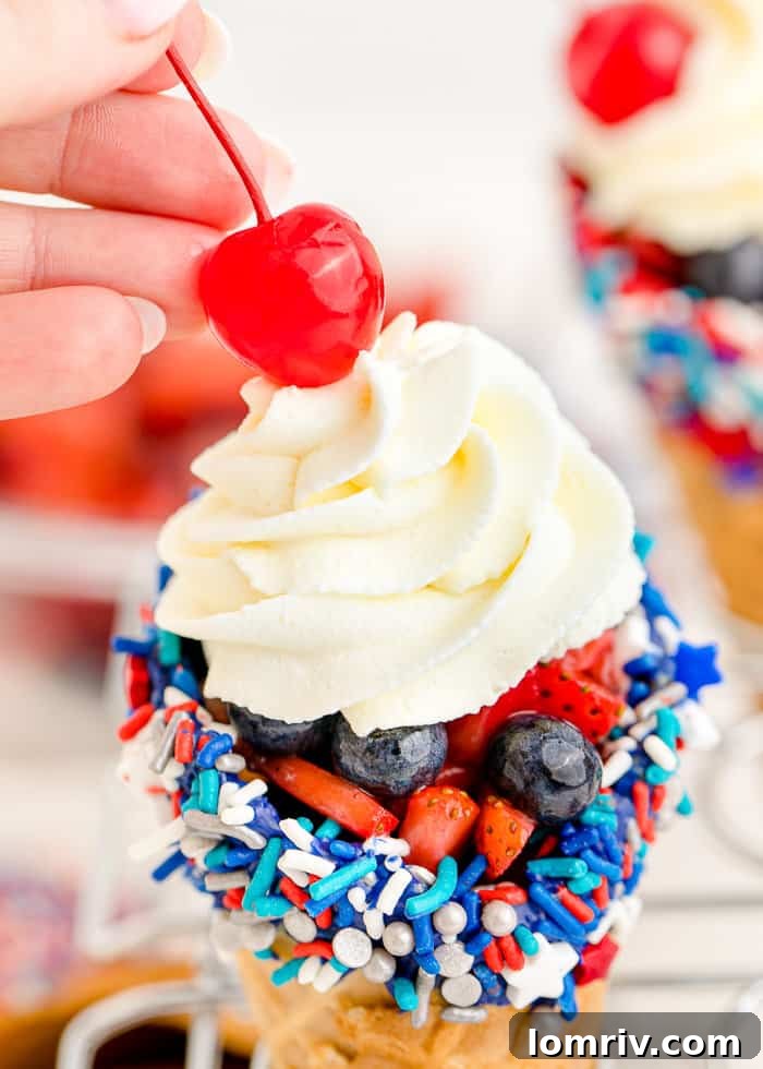 A maraschino cherry crowning the cheesecake stuffed waffle cone.