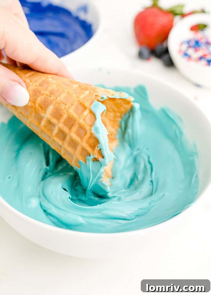 A waffle cone being dipped into vibrant blue melted candy.