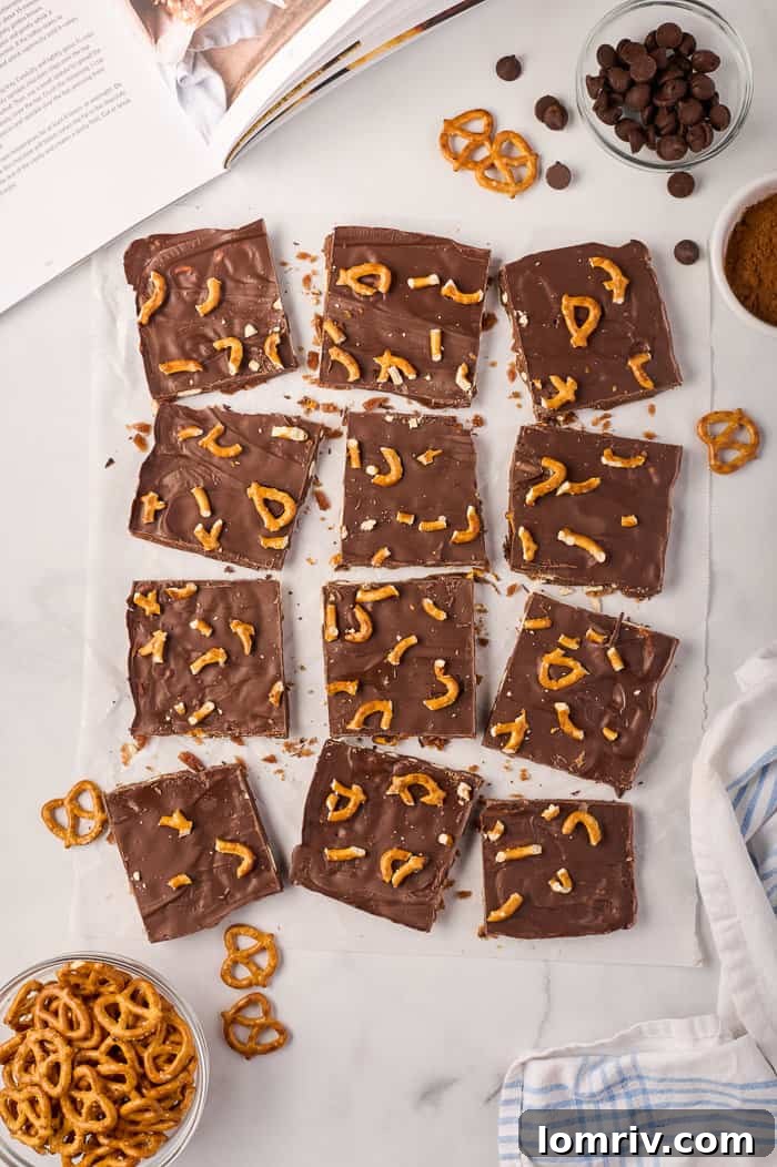 A festive display of pumpkin bark pieces, scattered with whole pretzels and spices, capturing the essence of fall desserts.