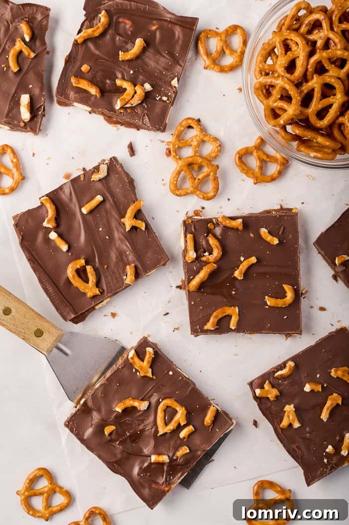 Pumpkin bark, freshly spread onto a baking sheet, with a spatula poised to smooth out the chocolate topping.