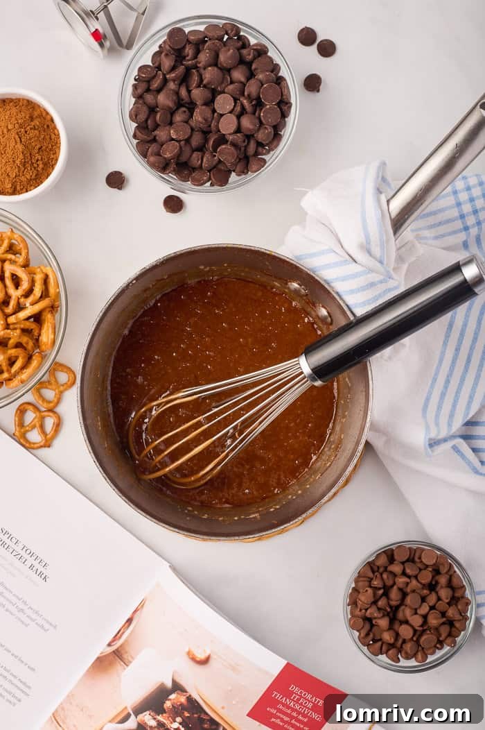 The toffee mixture for pumpkin bark, simmering and turning golden brown in a pot, indicating it's reaching the desired caramelization stage.