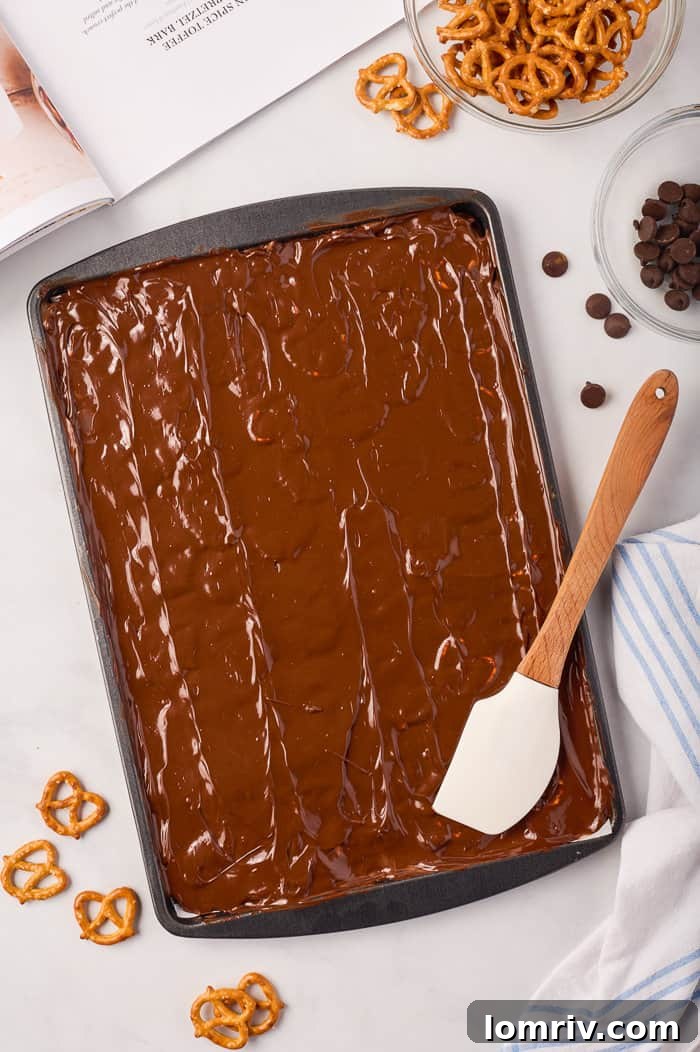 Hot, freshly made toffee for pumpkin bark poured onto a parchment-lined baking sheet, ready for the next layer.