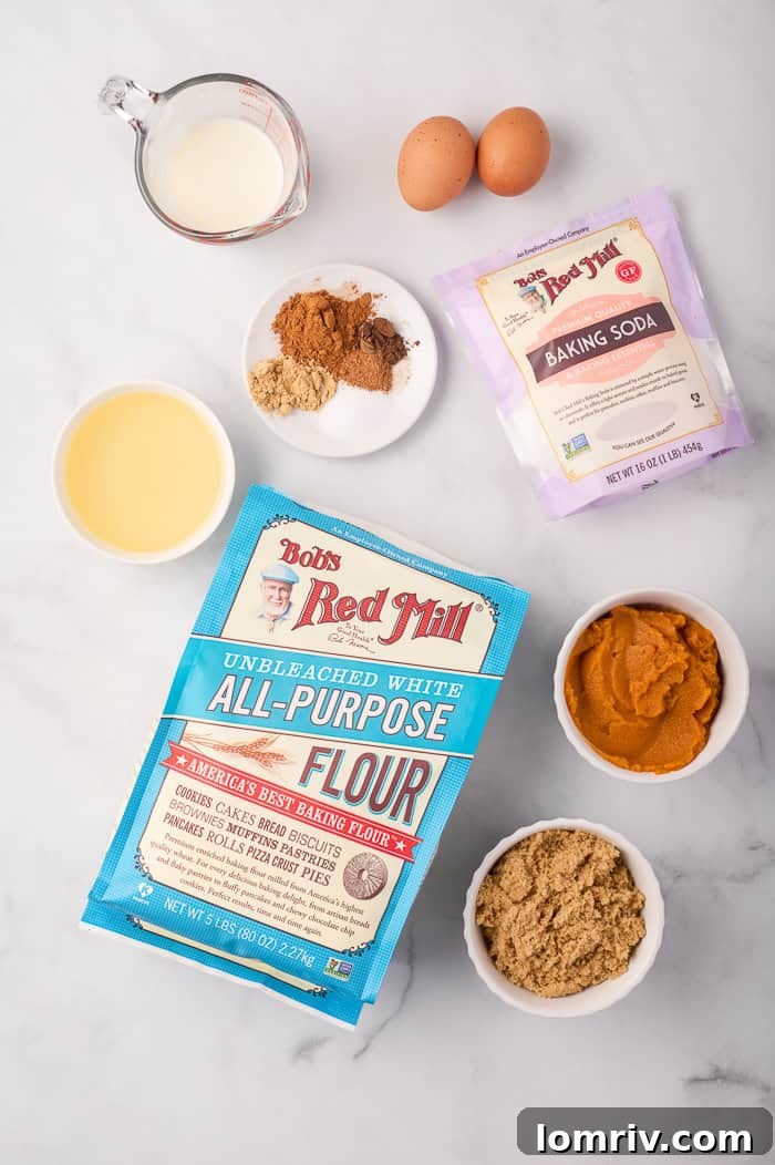 Various ingredients for pumpkin muffins, including flour, spices, and pumpkin puree, laid out on a surface.