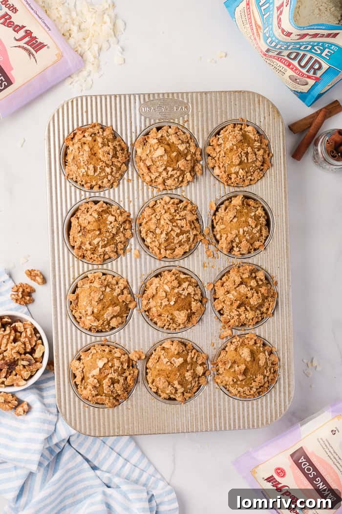 Freshly baked pumpkin muffins in a muffin pan, golden brown and puffed.