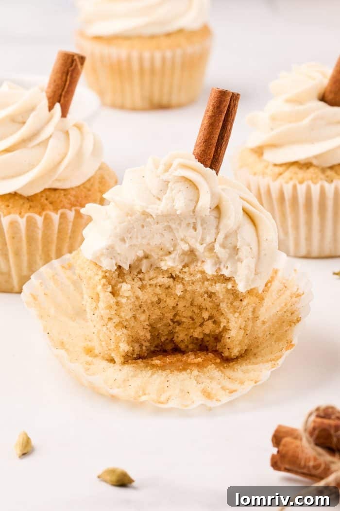 A close-up of a chai cupcake with a bite taken, revealing its moist, spiced interior, ready to be enjoyed.