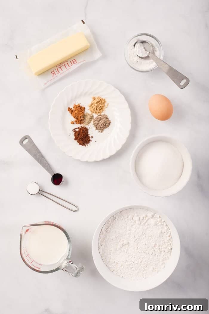 A collection of fresh ingredients laid out, including a homemade chai spice mix, butter, sugar, egg, vanilla, flour, baking powder, salt, and milk for the cupcakes.