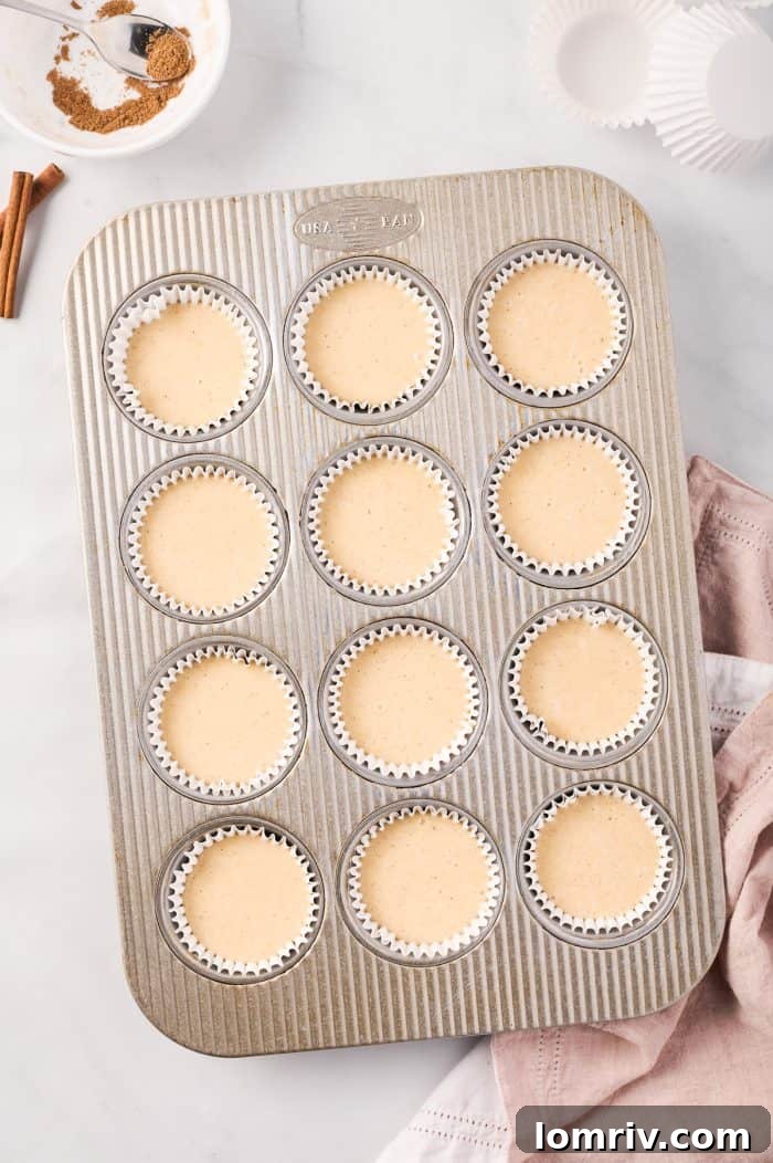 Chai cupcake batter neatly scooped into muffin liners, awaiting their transformation in the oven.