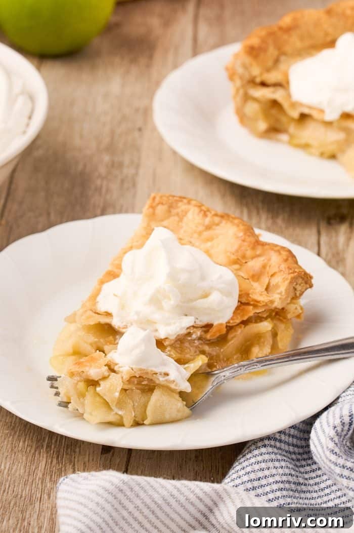 A slice of Maple Cream Apple Pie presented elegantly on a white plate.