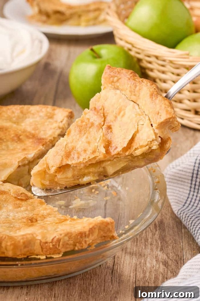 A slice of Maple Cream Apple Pie being gently lifted from the full pie, highlighting its gooey texture.