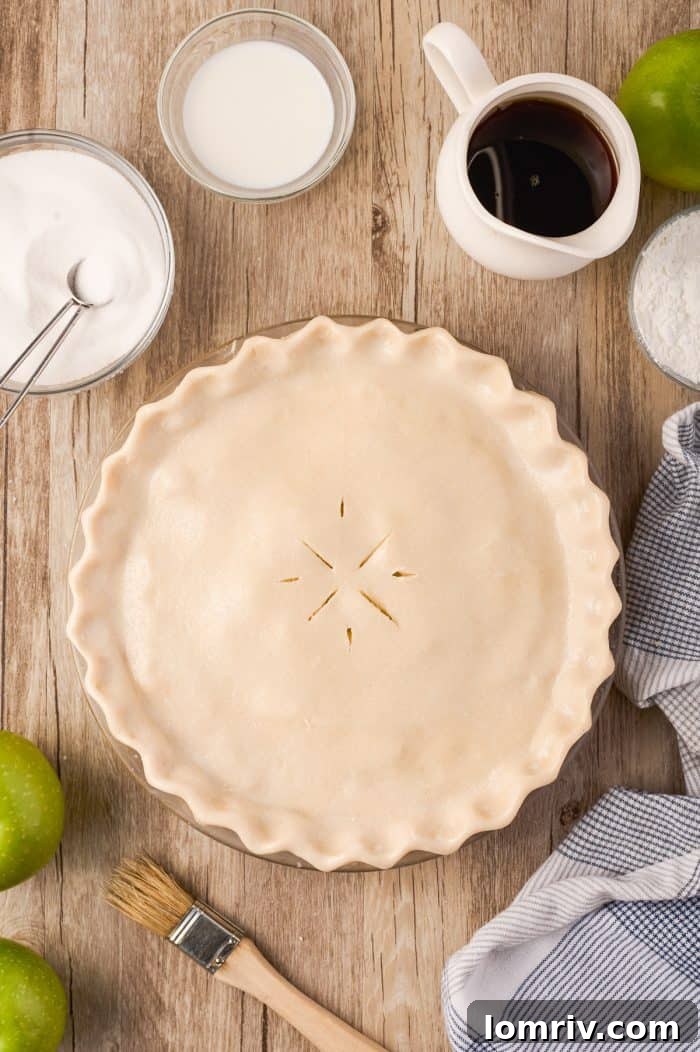 A close-up of an unbaked Maple Cream Apple Pie, showing the delicate sugar sprinkle on its top crust.