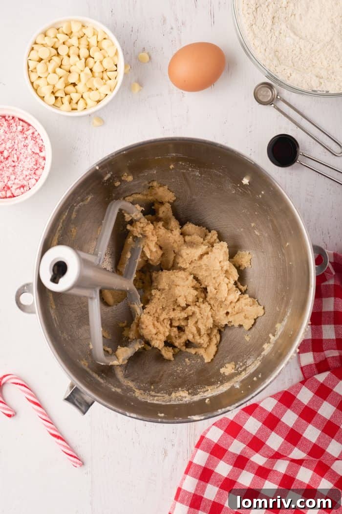 The wet ingredients for the cookie dough being mixed in a stand mixer, showing the creamy butter, sugar, egg, and extracts.