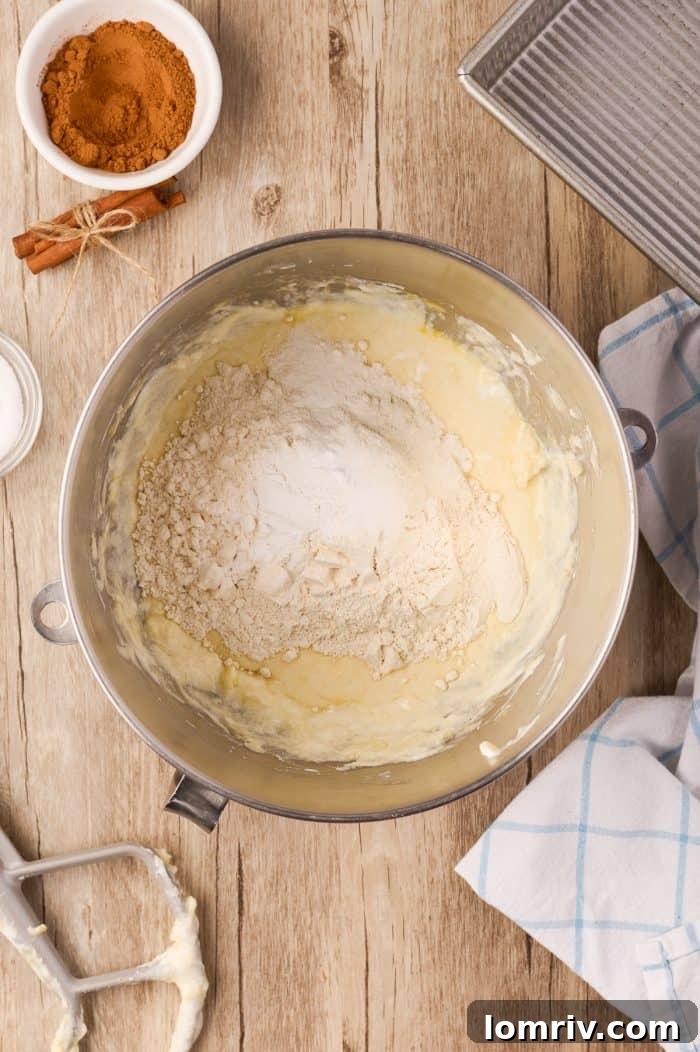 Dry ingredients being added to the wet cake batter in a mixing bowl.