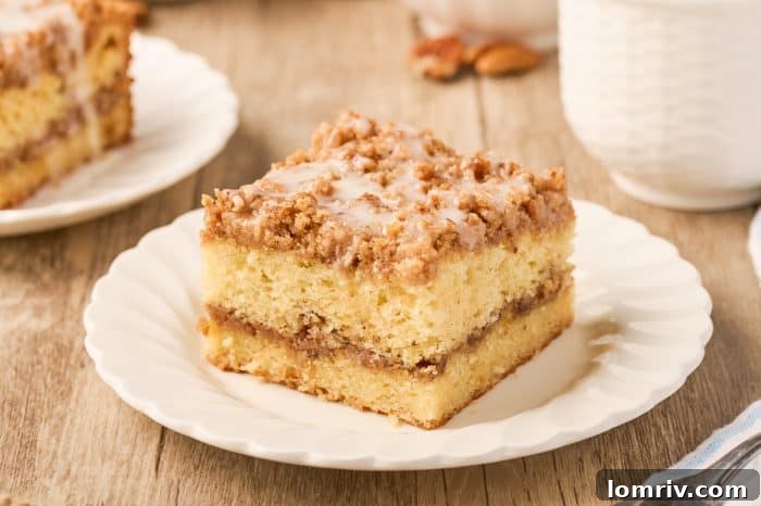 A perfectly portioned slice of sour cream coffee cake resting on a small white plate.
