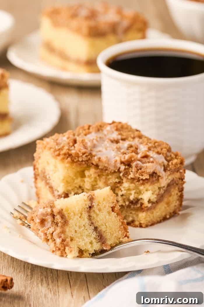 A fork holding a perfect bite of sour cream coffee cake, showcasing its moist crumb and streusel.