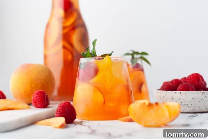 A glass and pitcher of peach rose sangria.