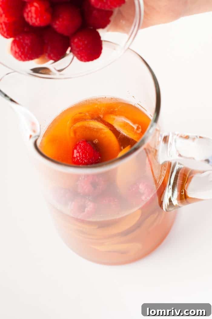 Adding raspberries to peach sangria.