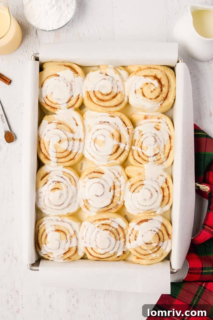 Baked Eggnog Cinnamon Rolls, golden brown and glistening, fresh out of the oven in their pan.
