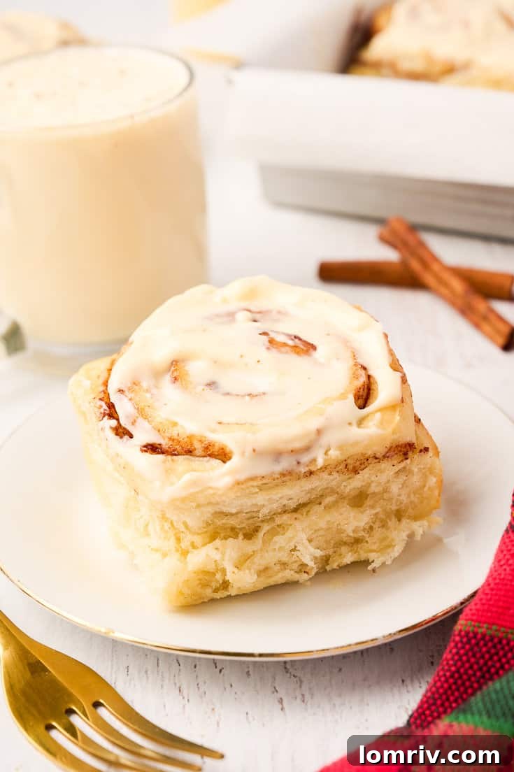Beautifully iced Eggnog Cinnamon Rolls on a festive plate.
