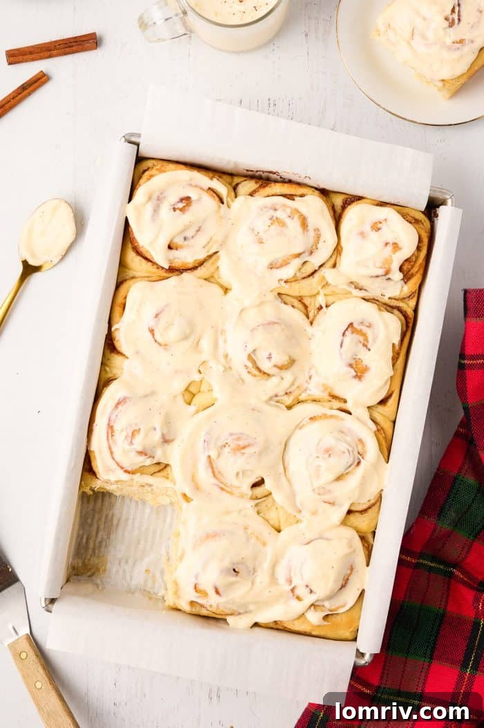Freshly baked Eggnog Cinnamon Rolls cooling in a baking pan.