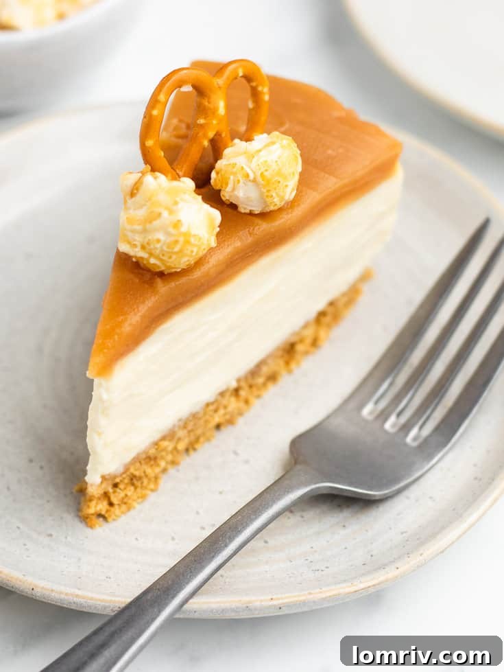 A perfectly sliced piece of no-bake caramel cheesecake served on a white plate, highlighting its distinct layers and generous caramel topping.