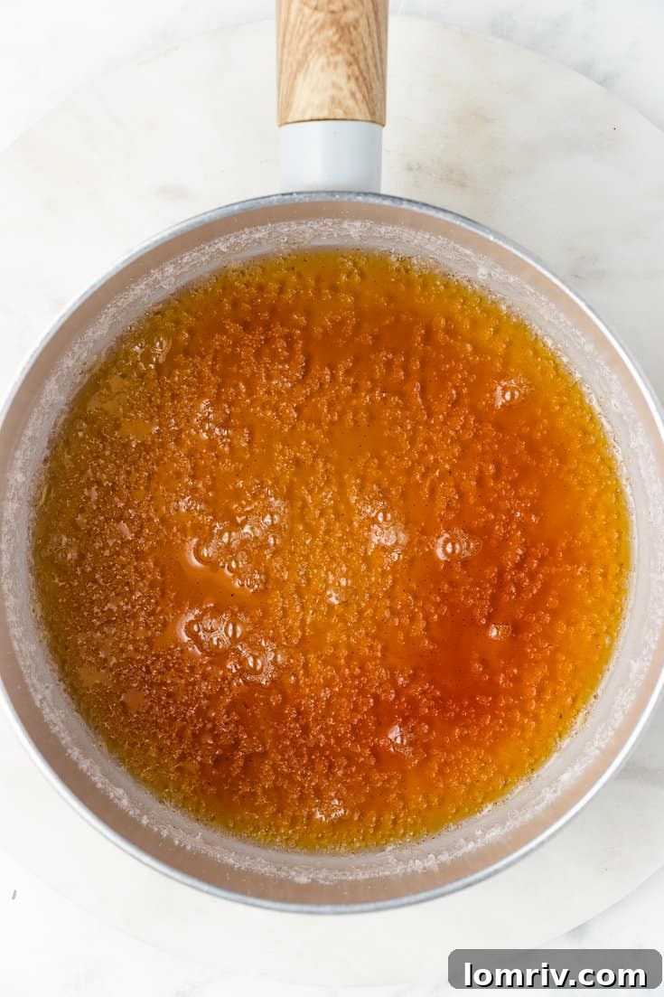 Granulated sugar and water simmering in a saucepan, beginning to transform into a golden caramel sauce.