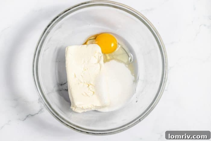 Ingredients for cheesecake filling being beaten in a separate bowl until smooth.