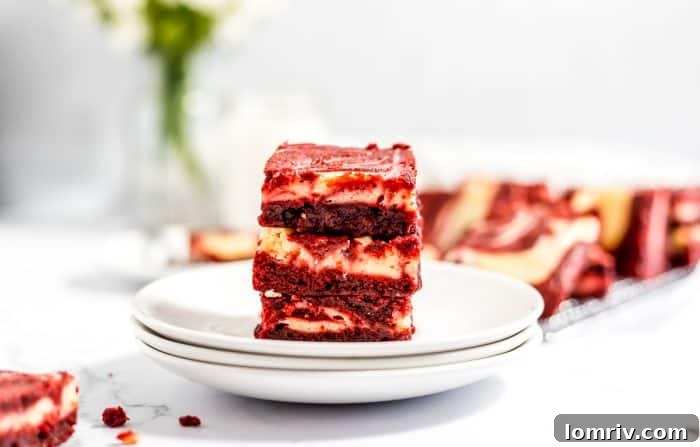 A single piece of red velvet cheesecake brownie presented on a white plate, invitingly cut to reveal its layers.