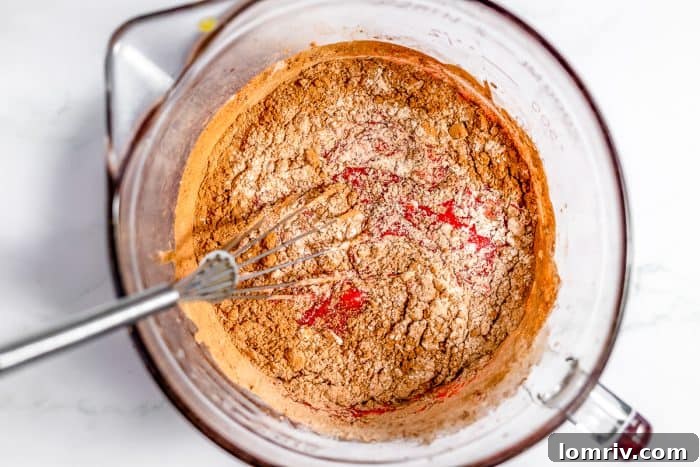 Dry ingredients for red velvet brownies being whisked into wet ingredients.