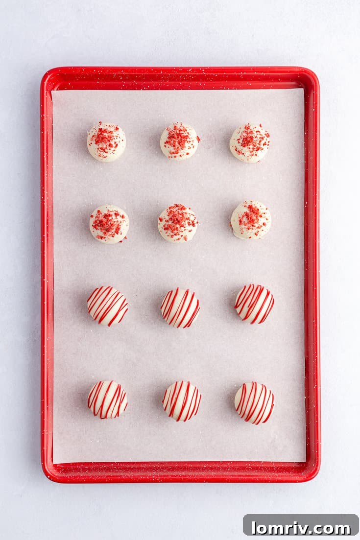 A strawberry cake ball being carefully dipped into a bowl of melted white vanilla chocolate, creating a smooth, even coating.