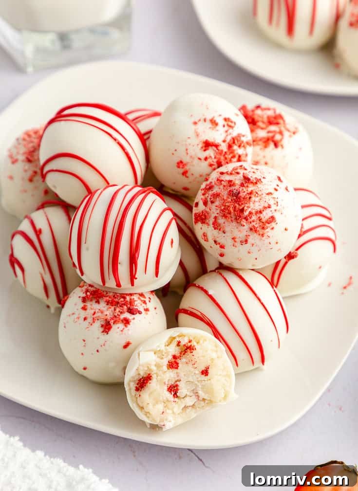 A plate of perfectly coated and decorated strawberry cake balls, glistening and inviting.