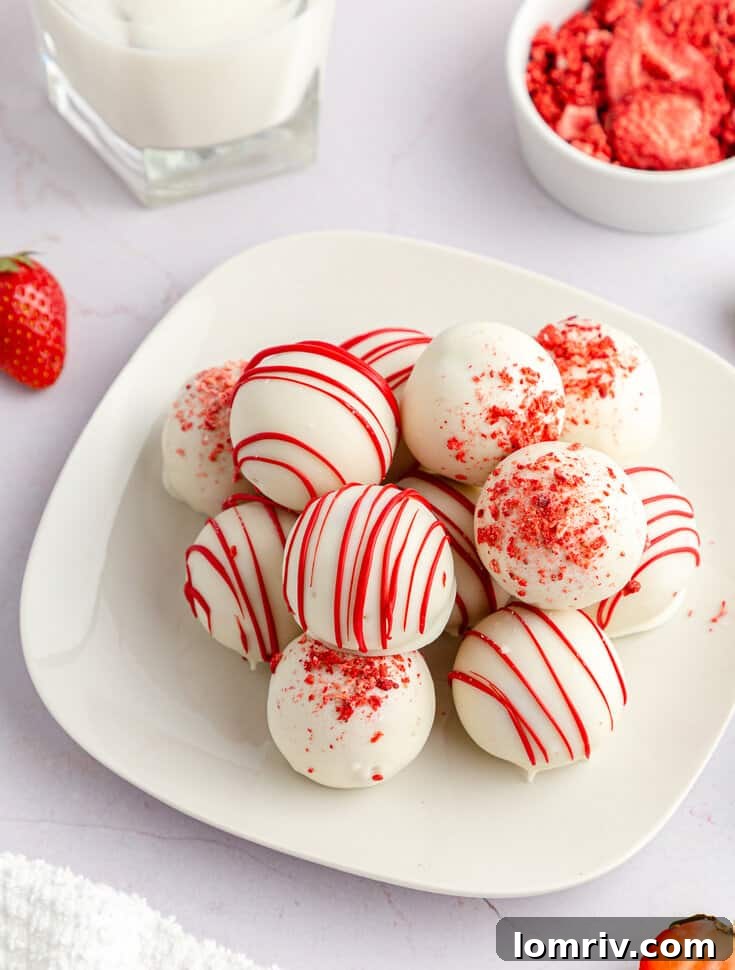 A close-up shot of a plate brimming with freshly made strawberry cake balls, showcasing their smooth coating and delightful pink centers.