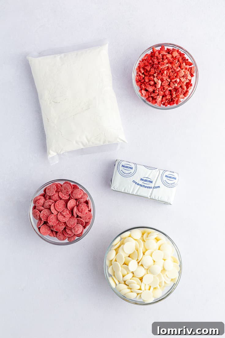 Various ingredients laid out for strawberry cake balls, including cake mix, cream cheese, freeze-dried strawberries, and melting wafers.