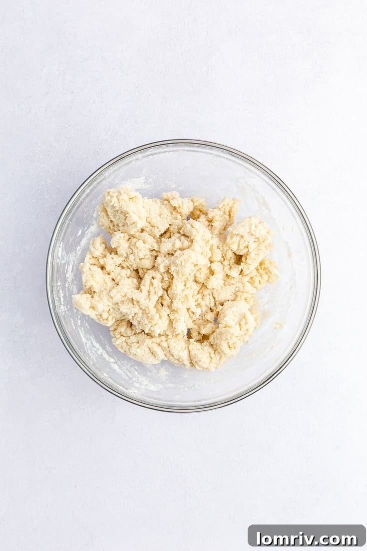 The cooled cake mix being combined with the softened cream cheese in a bowl, forming a thick dough.