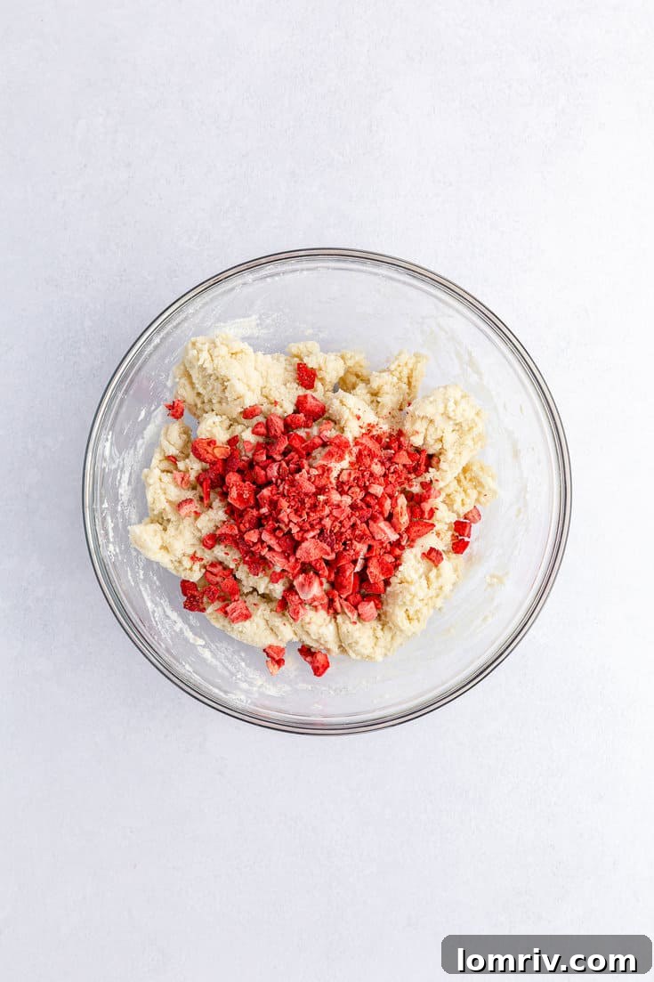 Freeze-dried strawberries being folded into the cake mix and cream cheese dough, adding color and flavor.