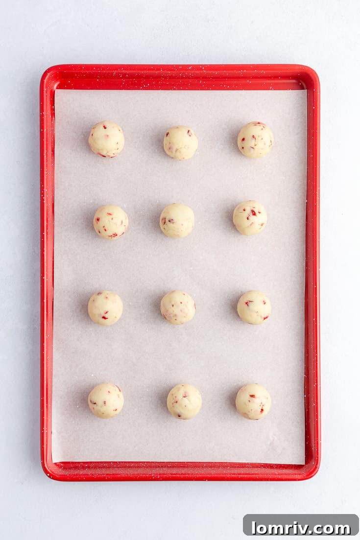 Portioned and rolled cake balls, chilled and waiting to be coated, neatly arranged on a parchment-lined baking sheet.