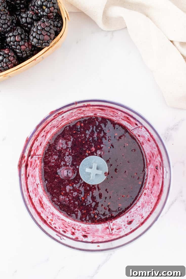 The blackberry mixture being blended into a smooth puree in a food processor.