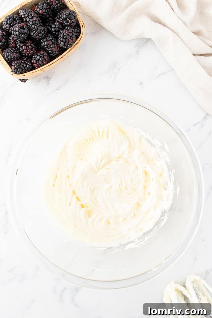 Softened butter being creamed in a large mixing bowl with an electric mixer.
