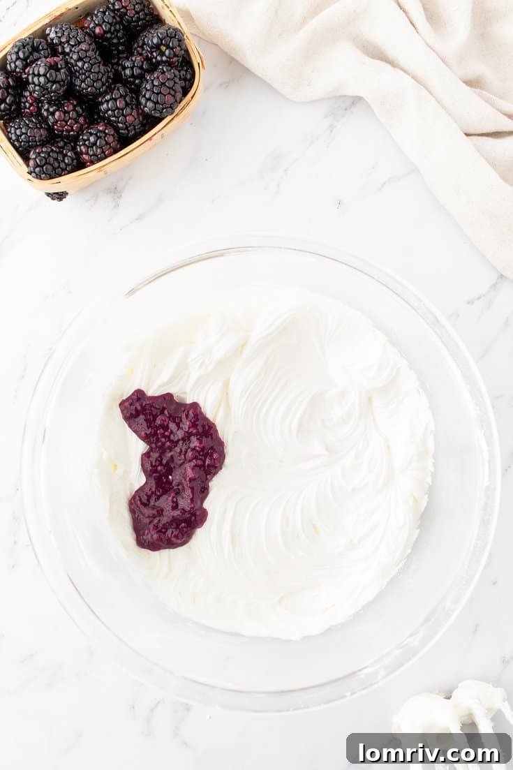 Blackberry filling being mixed into white buttercream frosting, creating a vibrant purple color.