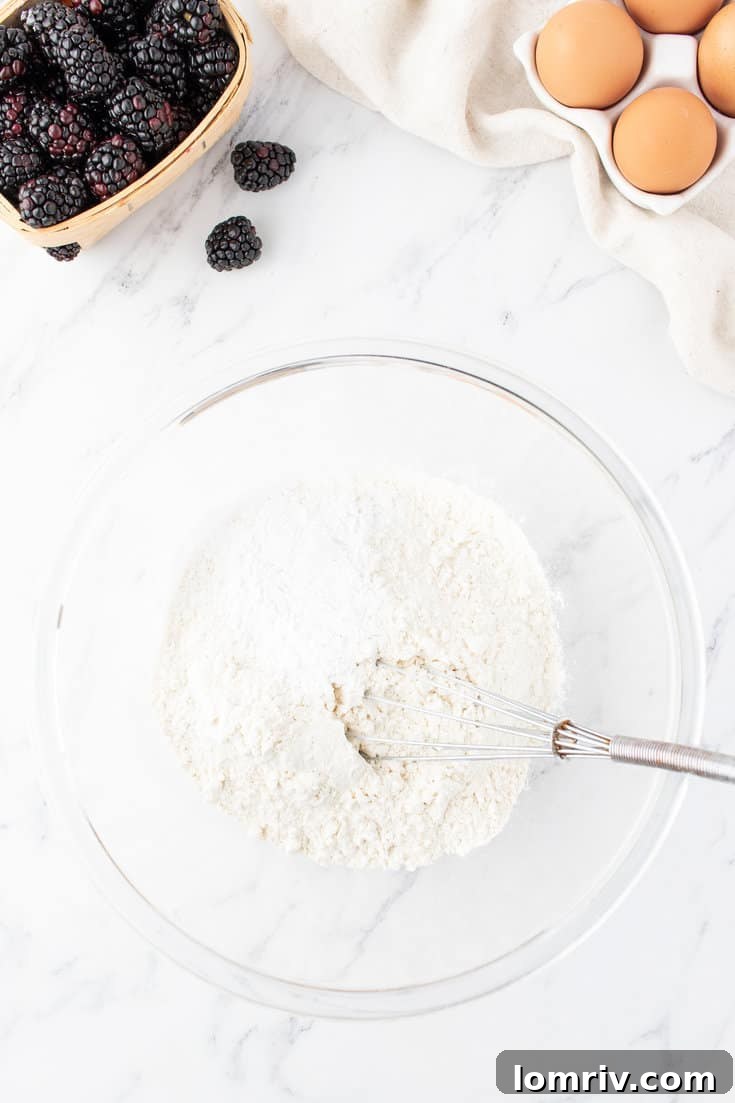 A person whisking flour, baking powder, and salt together in a white bowl.